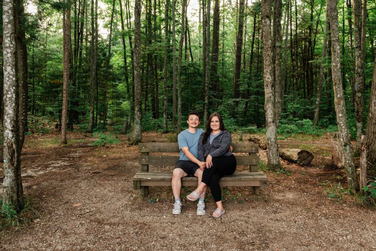 a man and woman sit on a bench at the head of the high rollaway trail for an engagement adventure.