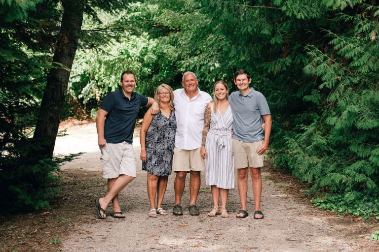 adult kids pose with their parents surrounded by pines.