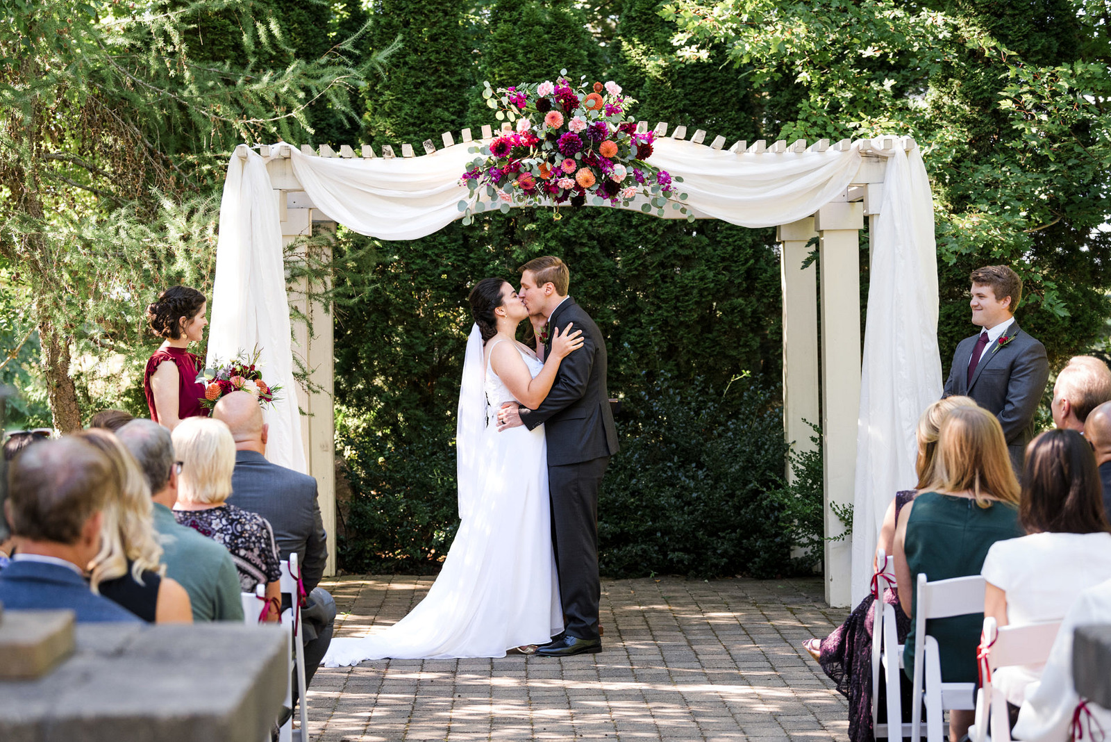 a bride and groom kiss under a white arch at fox hill event center in Cadillac, Michigan