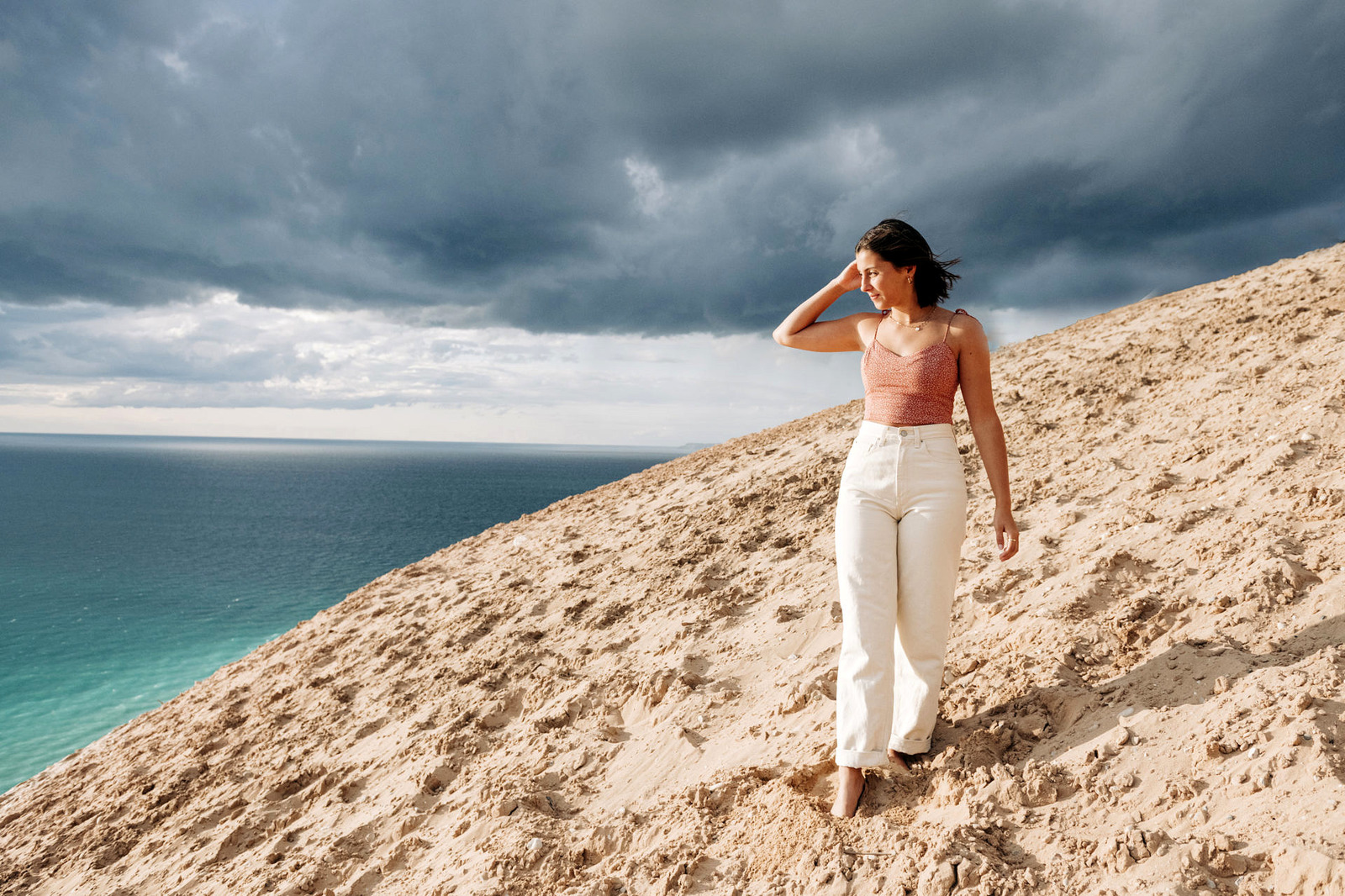 a slim girl on the point of sleeping bear dunes with lake michigan blue and wind