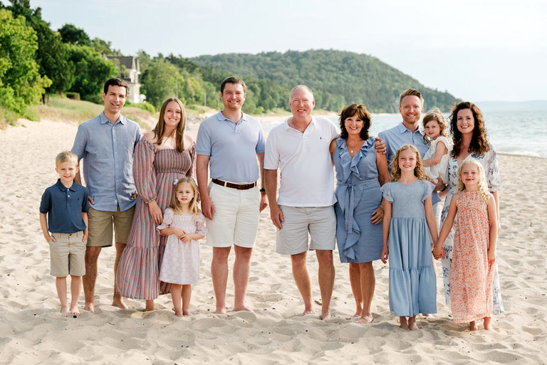a group with twelve family members stands on the beach in Leland for family portraits.