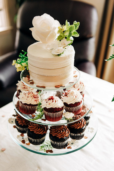 a small tower of a mini wedding cake and cupcakes
