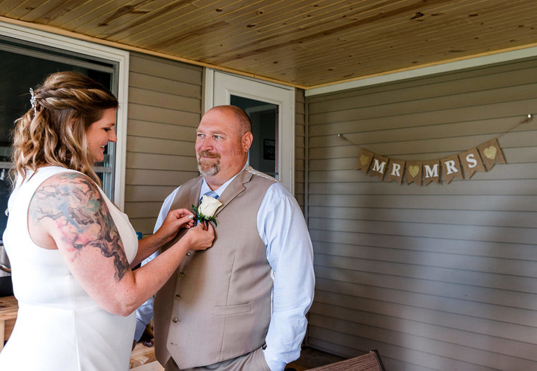 a tattooed bride pinning a flower onto the groom