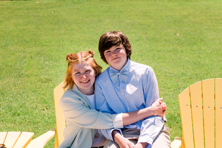 siblings hugging in a bright yellow chair
