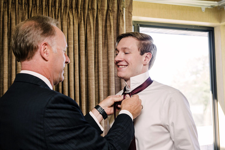 a young man having his tie adjusted by his father