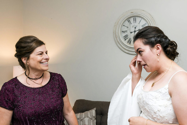 Bride wiping tears away with mom