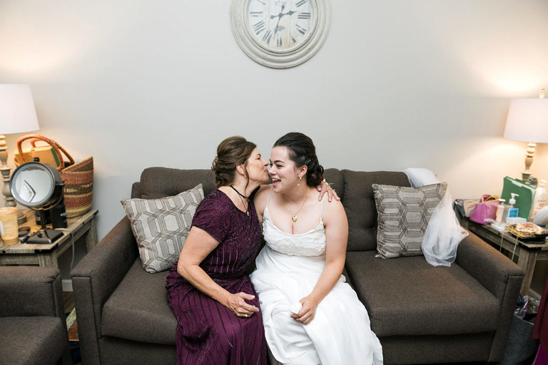 a woman and bride are seated and giving a kiss on the cheek at fox hill event center