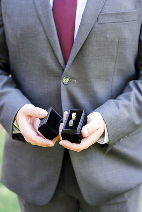 a man's hands hold a box with the couples wedding rings