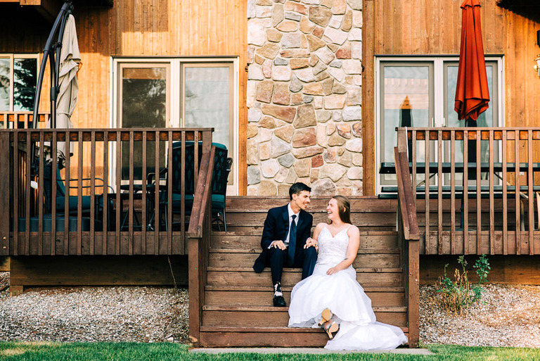 a bride and groom sitting on steps at the home on Elk Lake