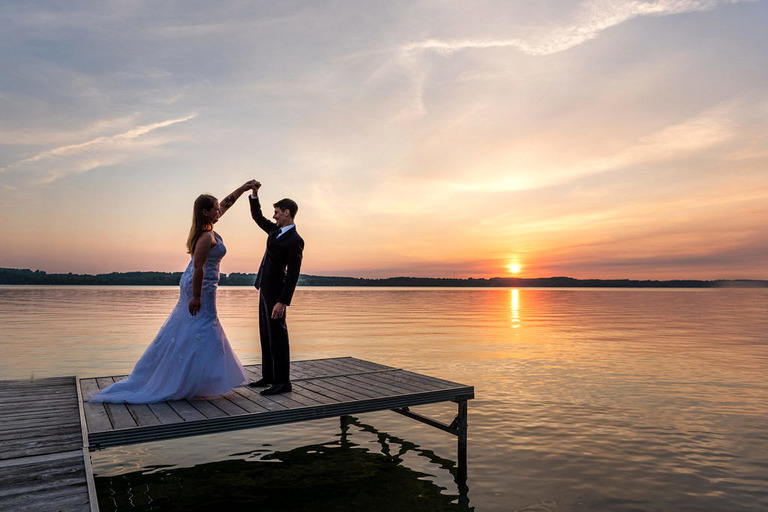 a married couple dances on a dock in Elk Lake at sunset