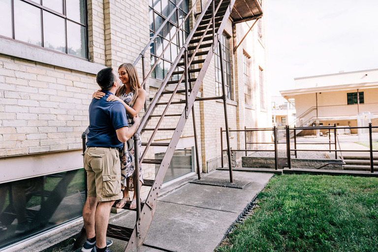 an engaged couple kisses on the fire escape in the Traverse City village