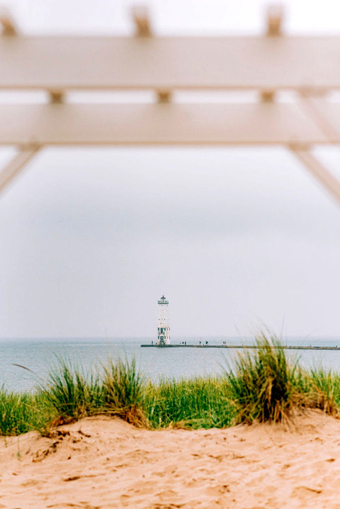 Frankfort michigan beach lighthouse seen through a wedding arch