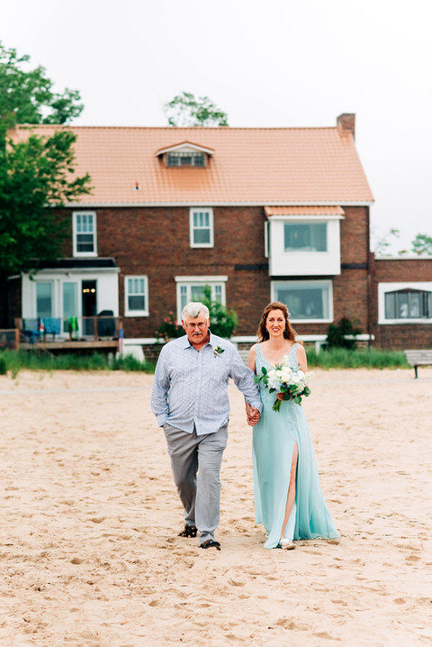 a wedding couple walking up to the ceremony site on Frankfort beach