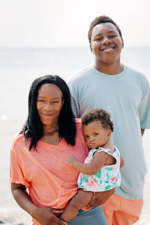 a close up photo of a smiling mom, daughter, and son at the empire, mi beach