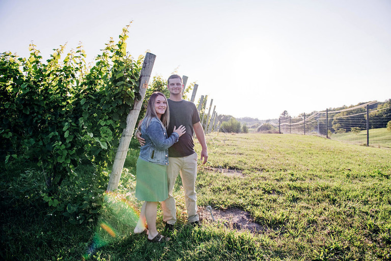 a couple stands in a vineyard in Arcadia mi with a sunflare