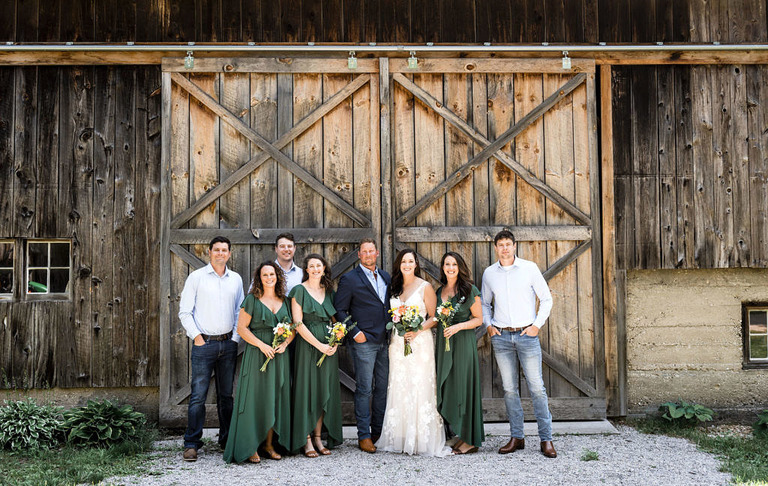 bridal party group photo in front of the barn doors at Iron Fish Distillery