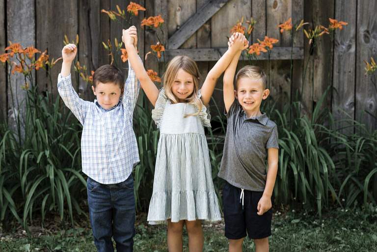 three little kids hold their hands up for a photo at Iron Fish Distillery