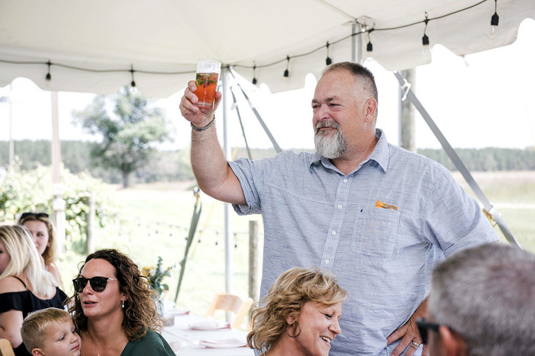 father of the bride raising a cocktail for a toast at Iron Fish Distillery