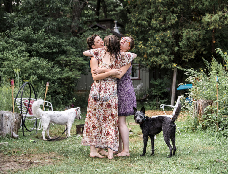 three women hugging with two dogs by them at Labrys resort mi