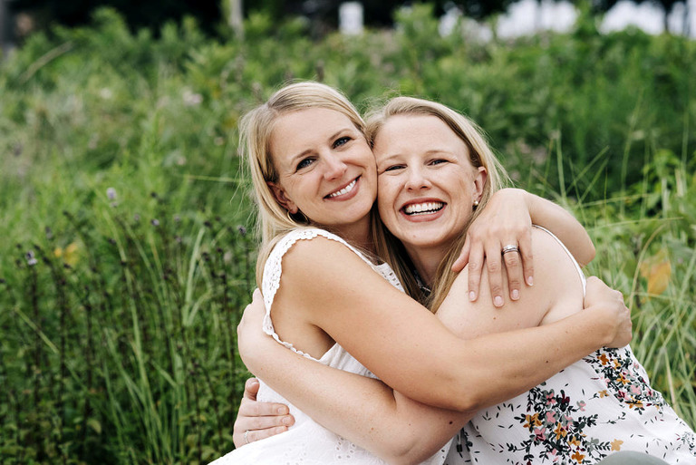 sisters hugging in front of beach grass