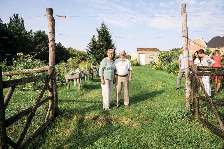 a senior couple stands inside the gates at the community gardens