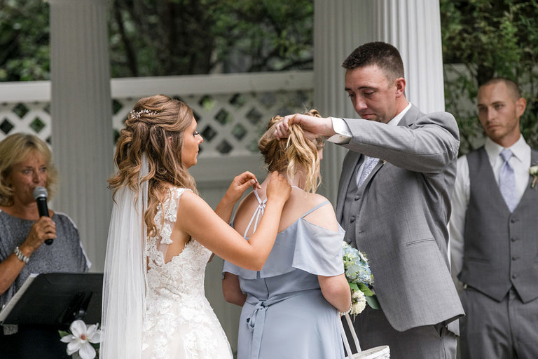 bride and groom give daughter a necklace during ceremony