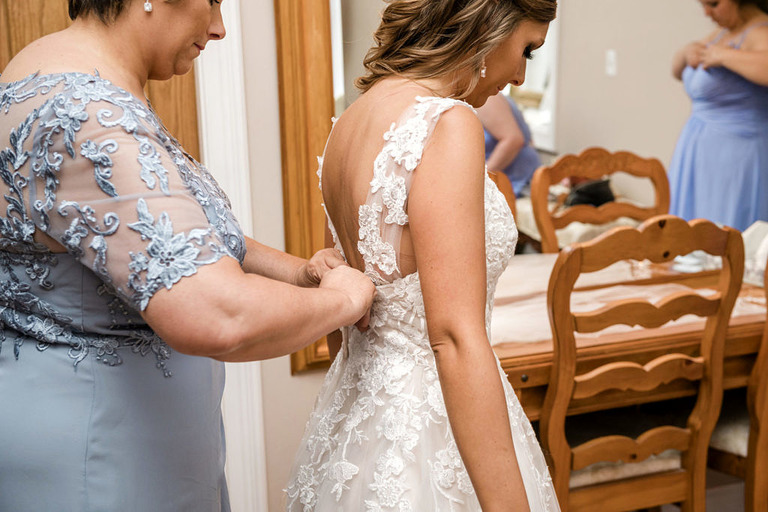 mother helping bride get dressed