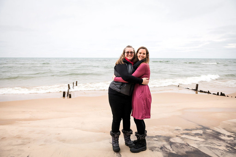 adult sisters hugging on the beach in manistee