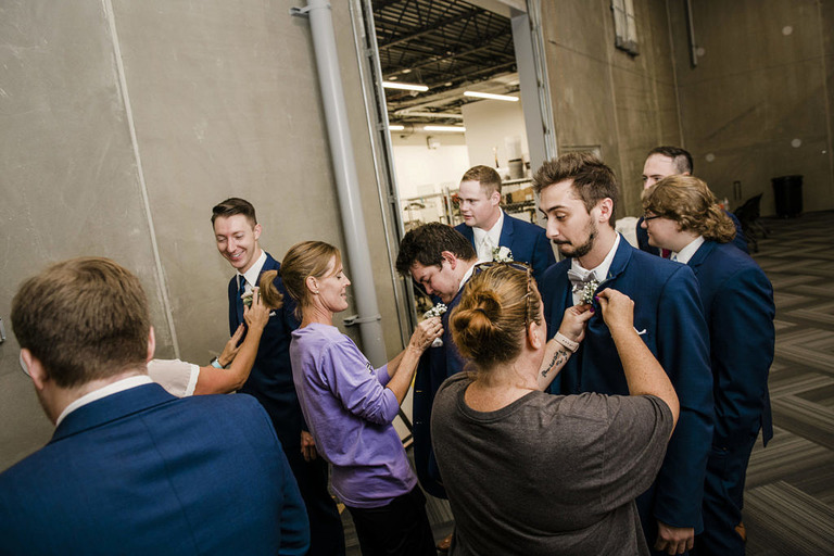 groomsmen getting boutonnieres pinned on at American 1 event center