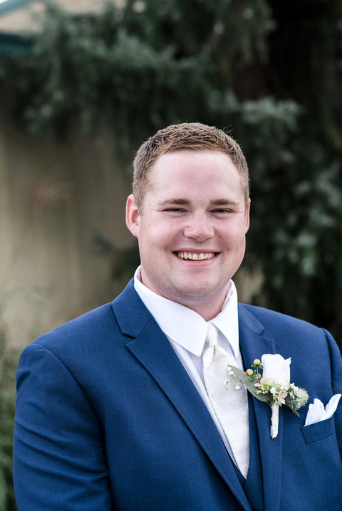 portrait of a groom in a blue suit at a wedding