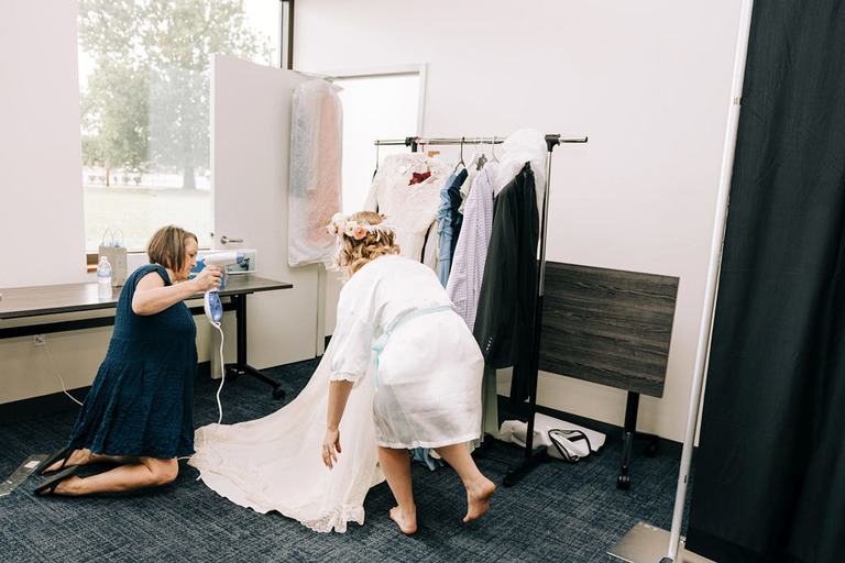 a bride helps steam her vintage wedding dress