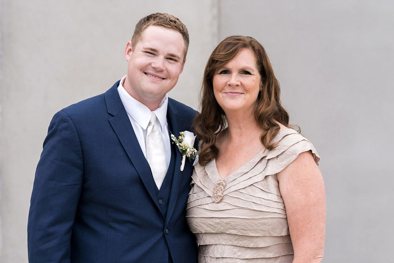 a groom in a blue suit with his mom