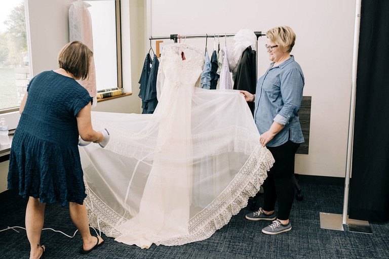 a vintage long sleeve wedding dress being steamed
