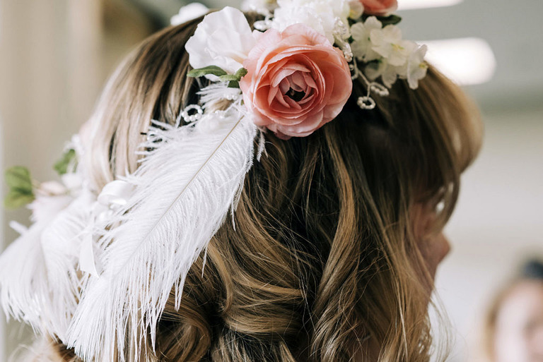 a brides head piece includes white feathers