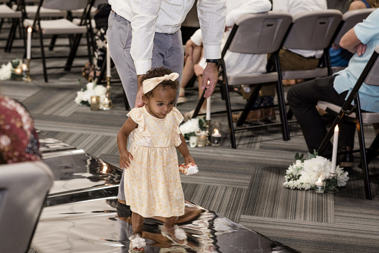 a little girl who is looking at her reflection in a metallic runner at a wedding