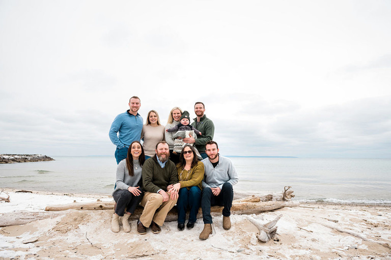 a large group sitting on the beach in Leland for a family pic
