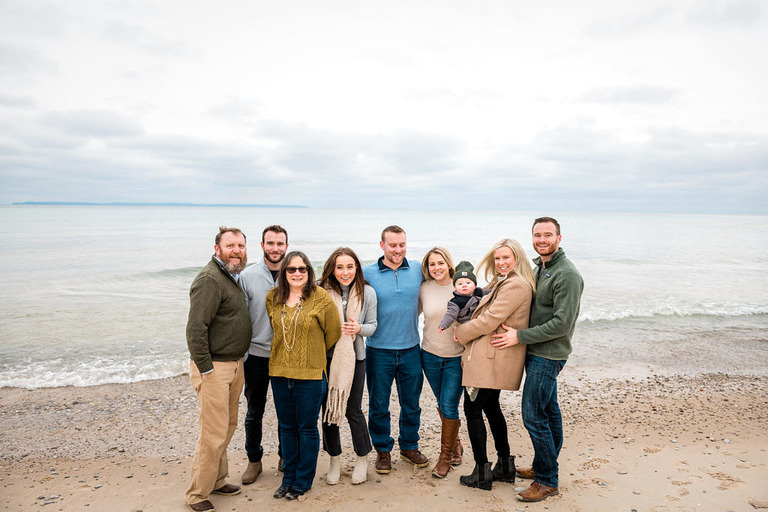 a large family group stands on the beach in leland, mi