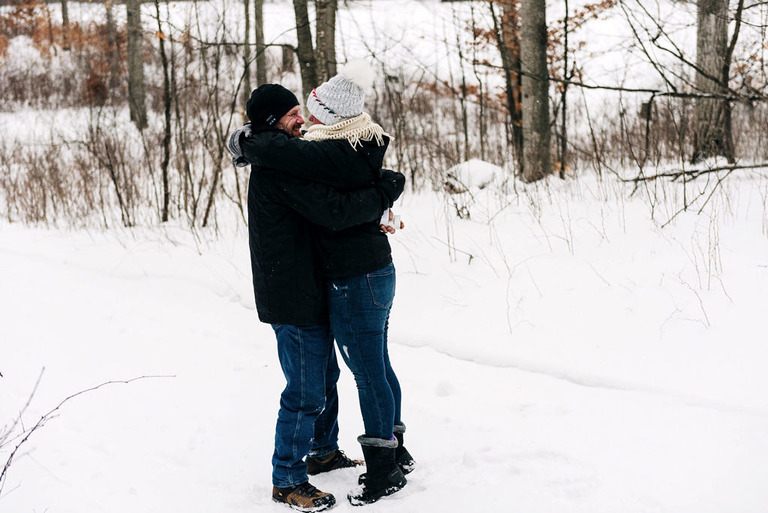 a man and woman kiss in the snow after a marriage proposal