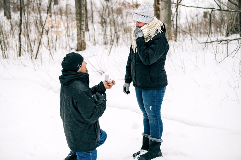 a man kneels in the snow to surprise propose to his girlfriend