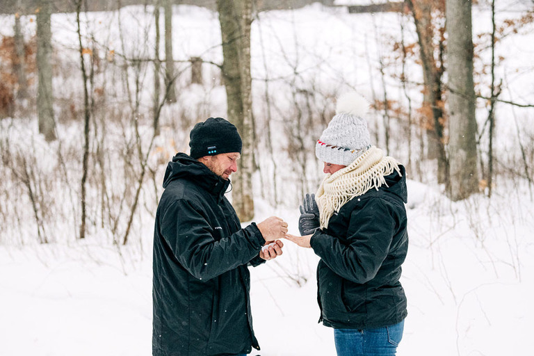 a man puts the engagement ring on his fiance at fantail farm