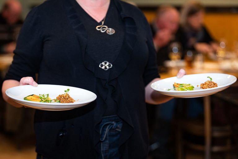 a server carrying two plates of the golden beet terrine