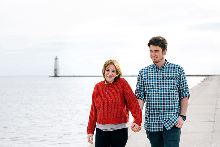 a couple is holding hands with part of the lighthouse in frame