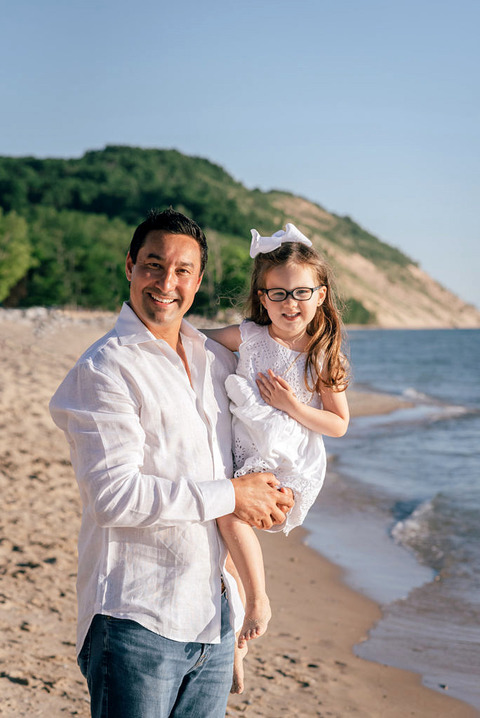 a dad holds his daughter by lake Miichigan in Empire