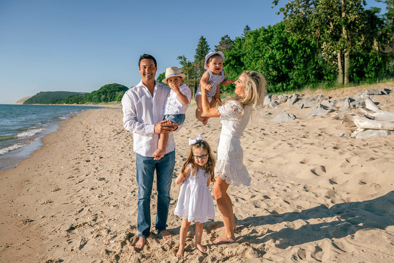 a family of 5 in all white plays on the beach
