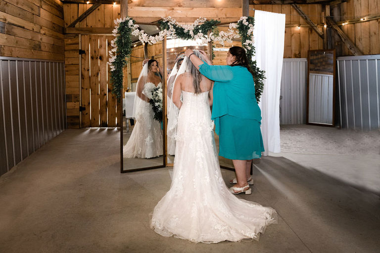 mother of the bride adjusting the brides veil in front of a full length mirror at Nugent orchards