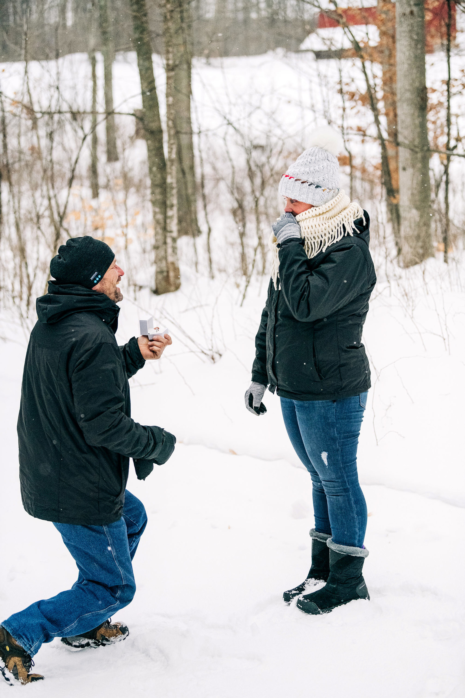 a man dropping to one knee to propose to his girlfriend at Fantail Farms in the snow