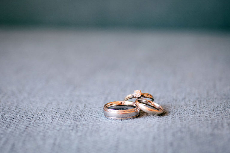 two wedding bands with the engagement ring stacked on a grey background