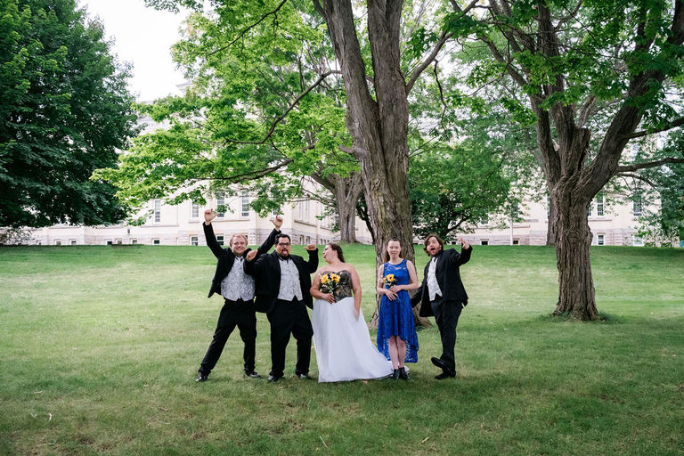 a wedding entourage has a fun portrait on the grounds of Kirkbride Hall