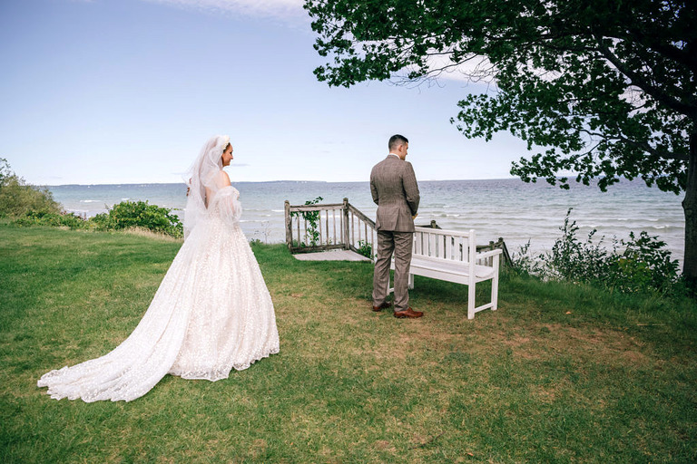 a couple having an intimate wedding moment. The bride is approaching the groom for a first look on the shores of lake MI