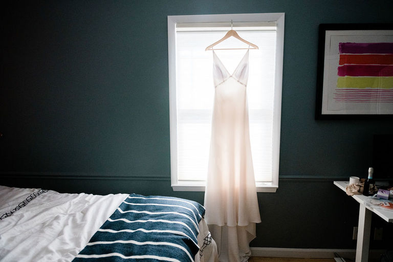 a slip style wedding dress hangs in a modern bedroom in Frankfort Michigan airbnb rental.